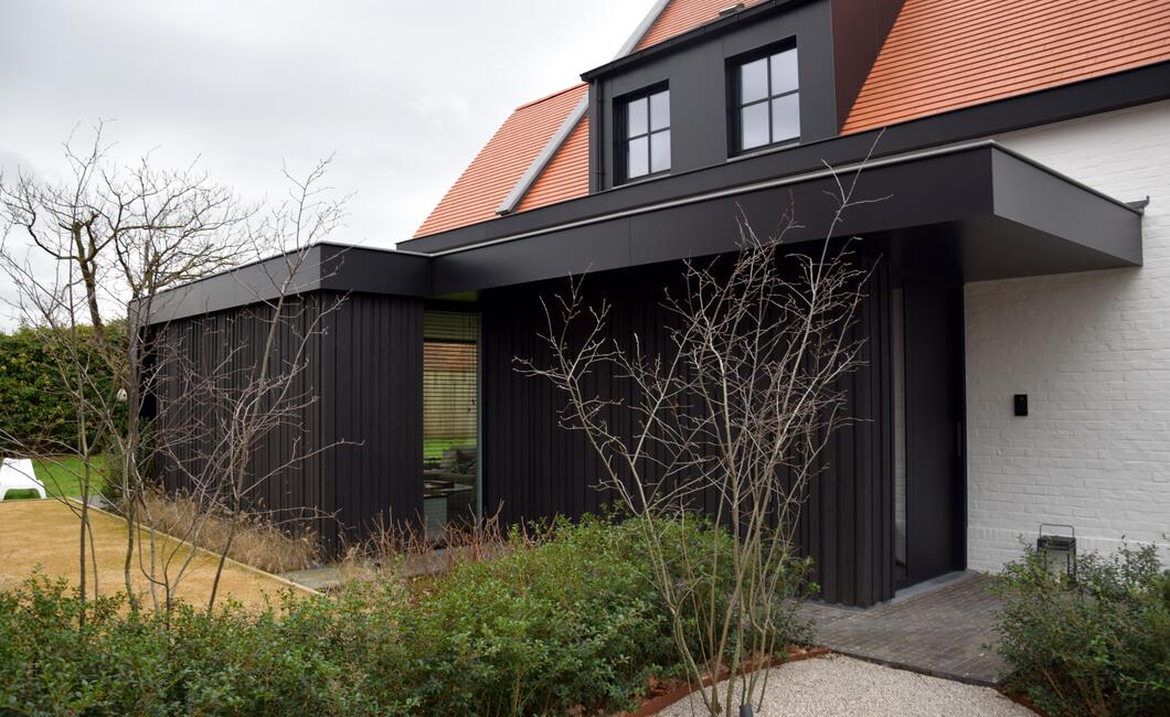 Wit geschilderde gerenoveerde villa met houten zwarte lariks gevelbekleding